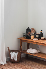 Simple scandinavian style bathroom interior - basket, slippers, jute carpet, oak bench with hygiene tools and accessories