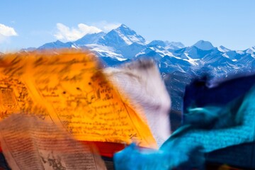 Experience the breathtaking grandeur of Mt. Everest as Tibetan prayer flags flutter in the wind, creating a colorful tapestry at Pang La pass (5248 m) near Tingri, Tibet.  - obrazy, fototapety, plakaty