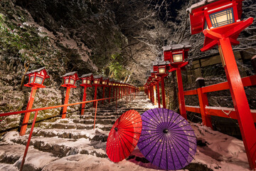 Kyoto, Japan. Kifune shrine traditional light pole in snowy winter night. Japanese umbrella on the...
