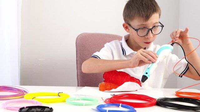 A boy draws or plays with a 3D pen