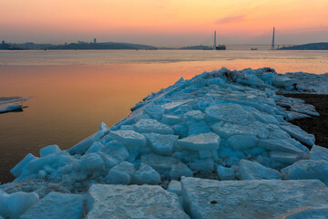 Winter Vladivostok. Russian bridge at dawn. A bright red sun rises behind the bridge. Eastern Bosphorus Strait.