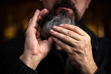 Closeup of a bearded man applying beard oil or serum, care treatment and men lifestyle