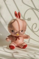 A doll wearing glasses sits at the window.
