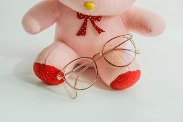 A doll wearing glasses sits at the window.