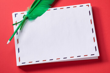 Stack of white greeting envelopes with a pen-shaped feather on a red background, template for...
