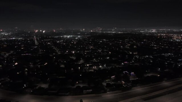 Drone timelapse of illuminated cityscape at night with fireworks in the background