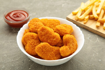 Homemade chicken nuggets and french fries with ketchup on grey background.