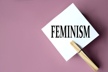 FEMINISM - word on white sheets of paper with clothespins on a coffee background