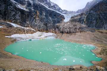 Encounter the majesty of Cavell Pond, a mountain mirrored in stillness. Witness the symphony of cascading glacier fragments, creating an arch in the emerald waters. Alberta, Canada. October 2021