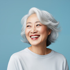 Beautiful mature Asian woman posing on a blue background. Mature woman smiles and feels satisfied.