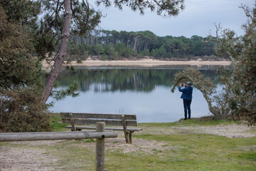 Senior woman taking a photo with her smartphone of Lake Vieux-Boucau in southwest France