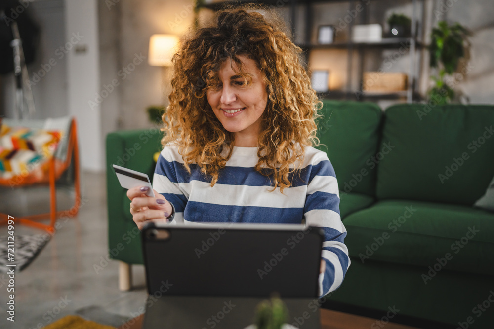 Wall mural young woman caucasian female hold credit card online shopping at home