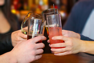 Young people cheering with drinks on their hands at a bar.