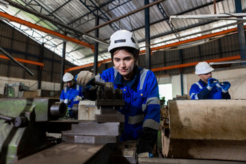 Naklejka na ściany i meble Asian female workers wearing uniform safety and hardhat working an iron cutting machine in factory Industrial. Engineering worker man work machine lathe metal. Heavy industry concept.