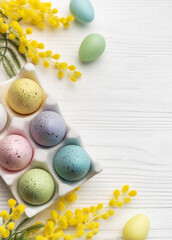 Colorful easter eggs  and mimosa flowers on wooden table.