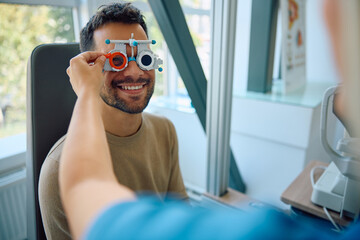 Happy man having his vision tested by ophthalmologist at eye clinic.