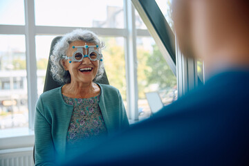 Cheerful senior woman with testing eyeglasses at ophthalmologist's.