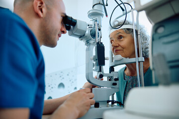 Senior woman during eye and vision exam at ophthalmologist's. - obrazy, fototapety, plakaty
