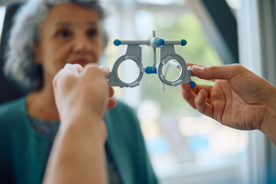 Close up of ophthalmologist using optical trial frame during patient's eyesight exam.
