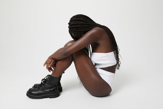 Thoughtful and sad African American woman with long braids posing indoor.