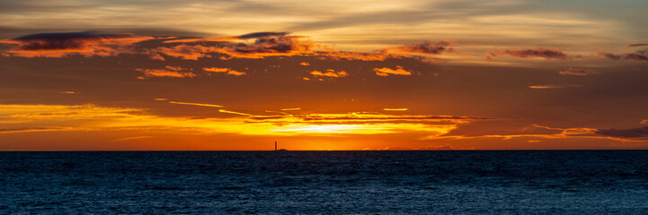 Phare à l'horizon au coucher du soleil