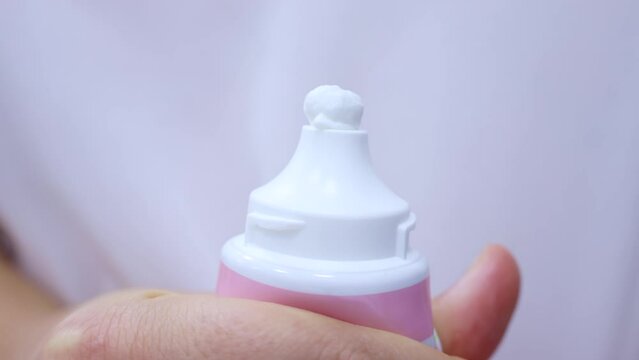Woman hand holding toothpaste tube and squeezing tooth paste close up