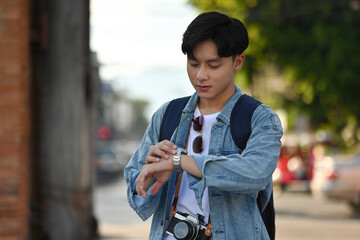 Handsome Asian tourist makes sure to check time for sightseeing in Chiang Mai