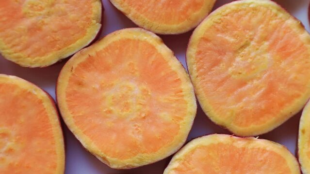 Fresh orange sweet potato slices circle rotation close up top view