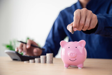 Man hand putting coins in pink piggy bank for account save money , Planning step up, saving money for future plan, retirement fund , Concept business finance saving money and investment.