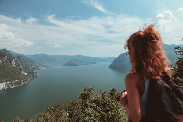 Young girl from behind with a black trekking backpack admires the naturalistic panorama before her...