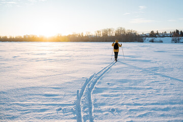 Ski tracks in the snow, man walking on cross-country skis in deep snow, evening skiing at sunset,...