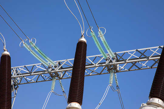 High voltage wires and insulators against a blue sky background.