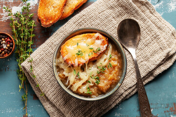 Classic French onion soup baked with cheese croutons sprinkled with fresh thyme. Top view