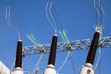 High voltage wires and insulators against a blue sky background.