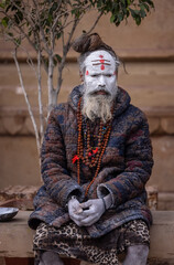Portrait of an holy sadhu baba with ash on his face sitting on ghats near river ganges in varanasi.