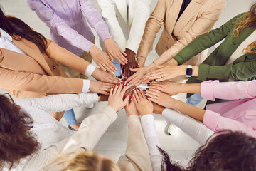 Team of diverse mixed race business women standing in circle in office and holding their hands...