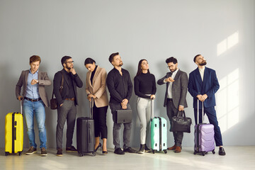 European business people in suits with bags and suitcases line up while standing inside the airport and waiting their turn to go to the check-in counters or boarding gate. Travelling by plane concept - obrazy, fototapety, plakaty