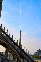 Spire with a statue against a blue sky at the Duomo di Milano (Milan Cathedral) in Milan, Italy