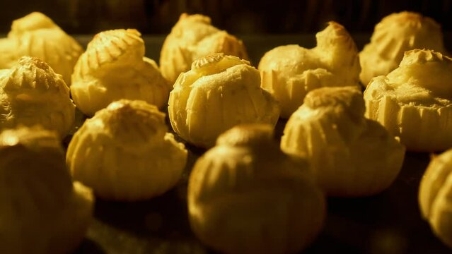 Profiteroles baking in oven. Homemade food growth in oven. Timelapse of profiterole production. Bakery concept. Brewing cake. Close-up in 4K, UHD