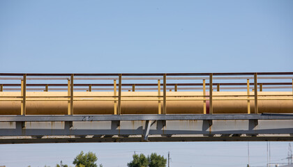 A yellow pipe with gas or liquid on a blue sky background.