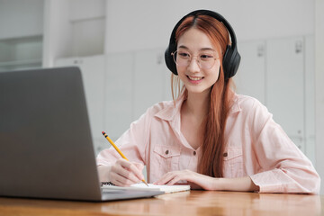 Young collage student using computer and mobile device studying online.