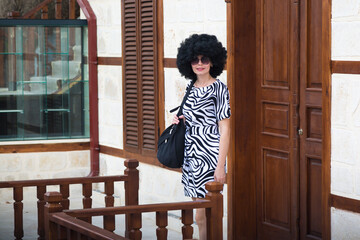 Young woman with black curly hair leaves home for work.