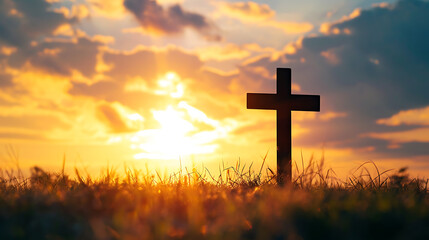 Silhouette cross on grass in sunrise background