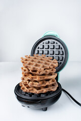 a stack of waffles lies in an electric waffle iron