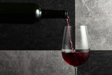 Fototapeta premium Red wine is poured from the bottle into a glass.