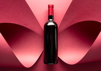 Bottle of red wine on a red background. - obrazy, fototapety, plakaty