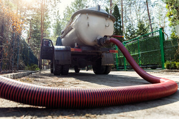 Close-up pipe hose of sewage truck car engine emptying home sewerage tank. Septic cleaning vacuum...
