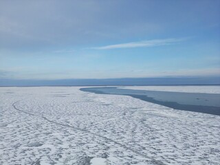 View from above. The river is covered with ice. A crack has formed on the surface of the water.