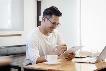 Happy middle aged business man ceo wearing suit sitting in office using digital tablet. Smiling mature businessman professional executive manager looking away thinking working on tech device.