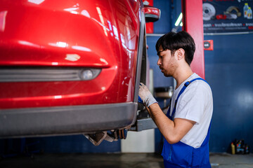 Auto mechanic is working under a vehicle that is servicing. checking and repairing customer cars